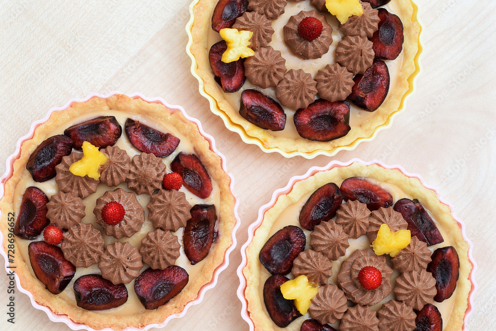 Fototapeta premium Shortbread tartlets decorated with whipped ganache and fruits (cherries, strawberries and nectarines cut out into a butterfly shape). Summer romantic baking