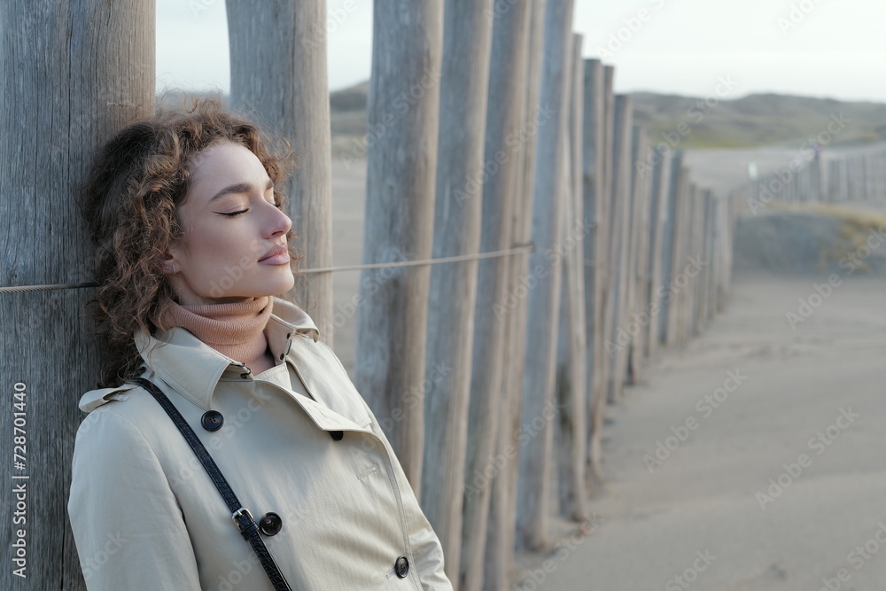Close up portrait of a beautiful young woman taking deep breaths with eyes closed on a sandy winter beach Close up portrait of a beautiful young woman taking deep breaths with eyes closed on a sandy winter beach