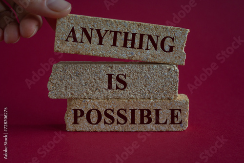 Anything is possible symbol. Concept words Anything is possible on beautiful brick blocks. Beautiful red background. Businessman hand. Business anything possible concept.