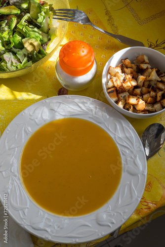 Plato con crema de verduras, tostones de pan frito y ensalada