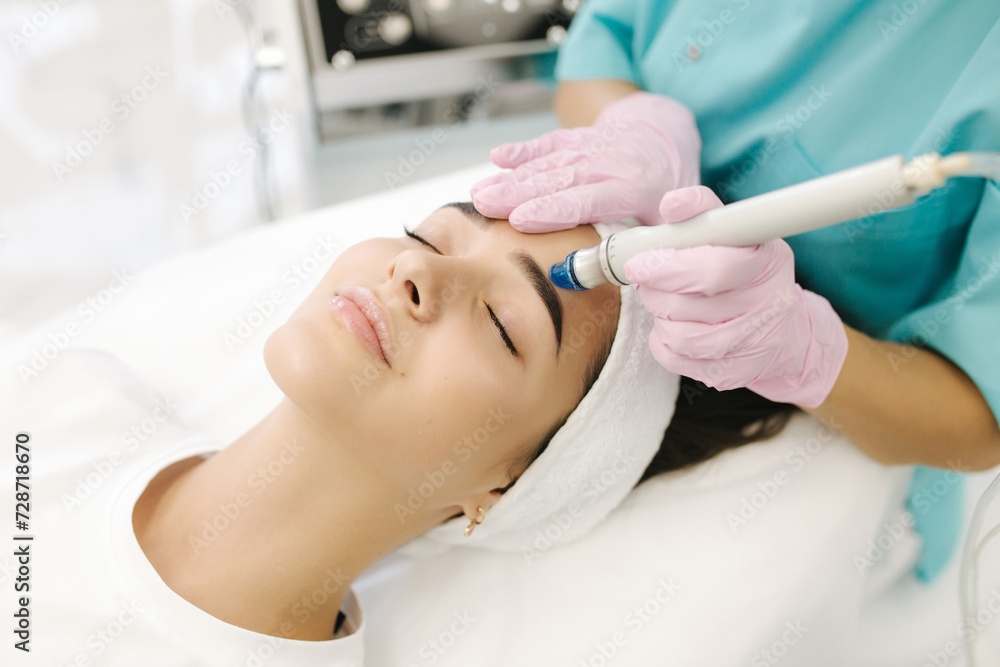 Close-up of woman getting facial hydro microdermabrasion peeling treatment. Female at cosmetic beauty spa slinic. Hydra vacuum cleaner. Cosmetology