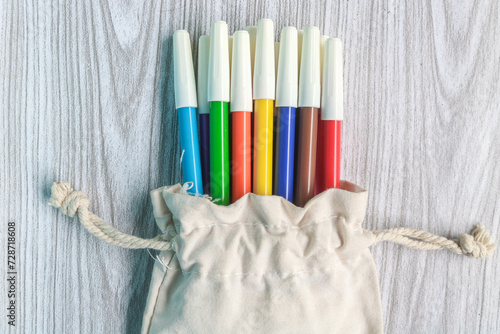 Colorful markers in a white drawstring bag photo