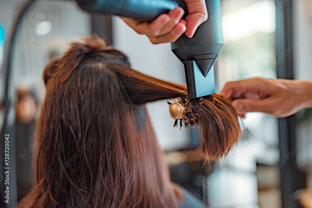 Naklejka premium Close-up Hairdresser drying clients hair working with professional tools in beauty salon or barber shop, Hair care concept, Small business