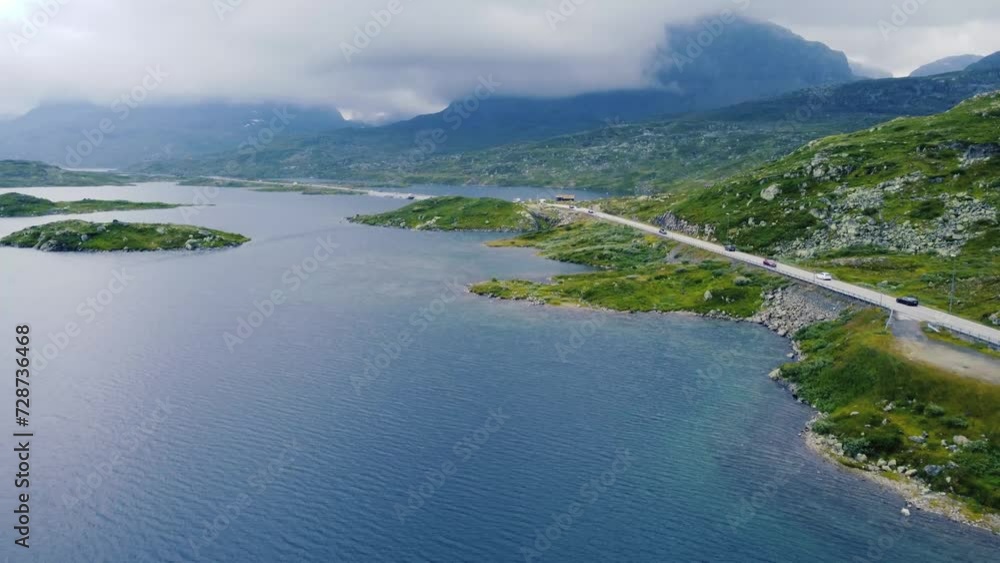 view of a lake and green hills in Norway, Hardangervidda, with a spectacular road crossing the lake view of a lake and green hills in Norway, Hardangervidda, with a spectacular road crossing the lake