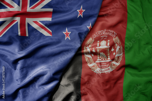 big waving national colorful flag of afghanistan and national flag of new zealand .