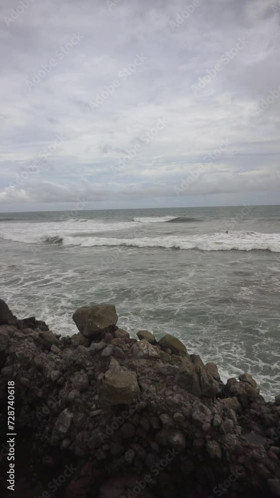 Beautiful vertical video of beachside views, natural panoramas, sea water accompanied by crashing waves and coral rocks with cloudy skies in the afternoon, on Karang Paranje beach, Garut Beautiful vertical video of beachside views, natural panoramas, sea water accompanied by crashing waves and coral rocks with cloudy skies in the afternoon, on Karang Paranje beach, Garut