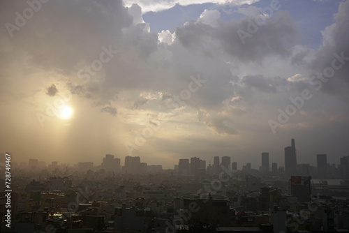 Sunshine glares through cloudy raining sky above city skyline © hippomyta