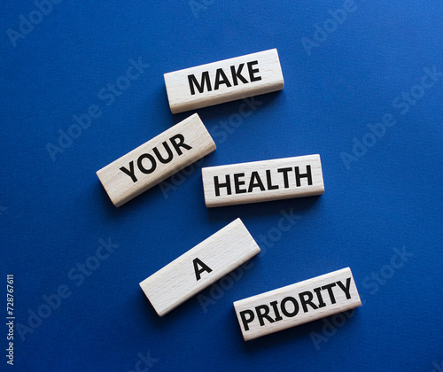 Health symbol. Wooden blocks with words Make your health a Priority. Beautiful deep blue background. Health concept. Copy space.