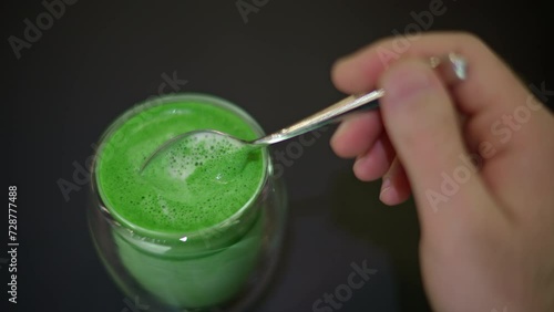 Woman stiring green matcha foam with spoon photo