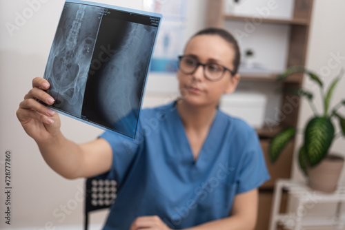 doctor in blue scrubs intently analyzes a radiology X-ray film to provide healthcare services and diagnose the patient in the hospital