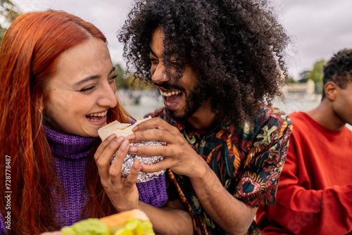 ethnic friends sharing a sandwich and laughing