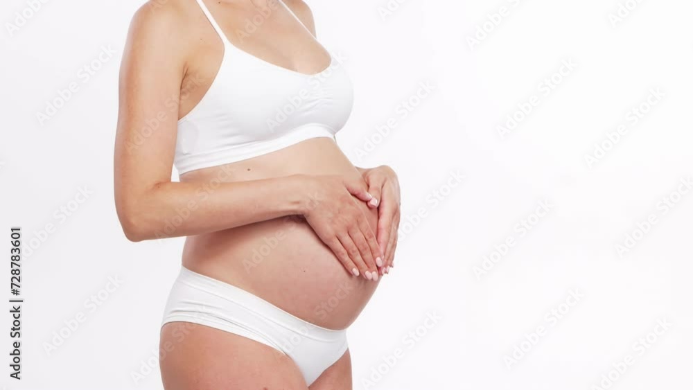 Young, happy and healthy pregnant woman in front of white background. Studio video. Baby expectation, pregnancy and motherhood. Young, happy and healthy pregnant woman in front of white background. Studio video. Baby expectation, pregnancy and motherhood.
