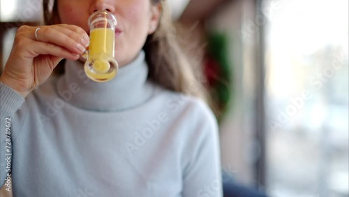 Woman drinking vitamin ginger immunity shot in a restaurant photo