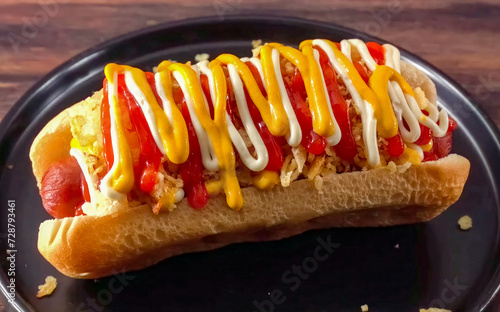 Hot Dog Colombian Grilled with Yellow Mustard and Ketchup, minimal close up. Hot dog freshly baked on plate, homemade. Grocery product advertising, menu or package, selective focus.