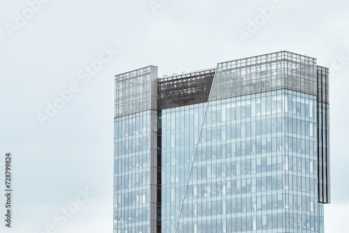 High-rise office building. A modern glass building stands tall against a cloudy sky showcasing architectural brilliance and urban development.