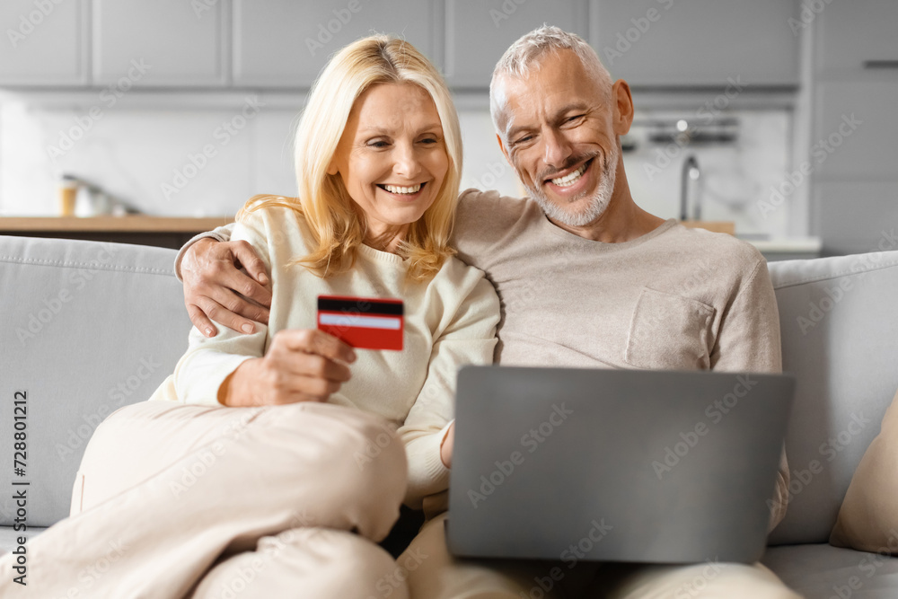 Smiling attractive caucasian retired man and woman shopping online together Smiling attractive caucasian retired man and woman shopping online together