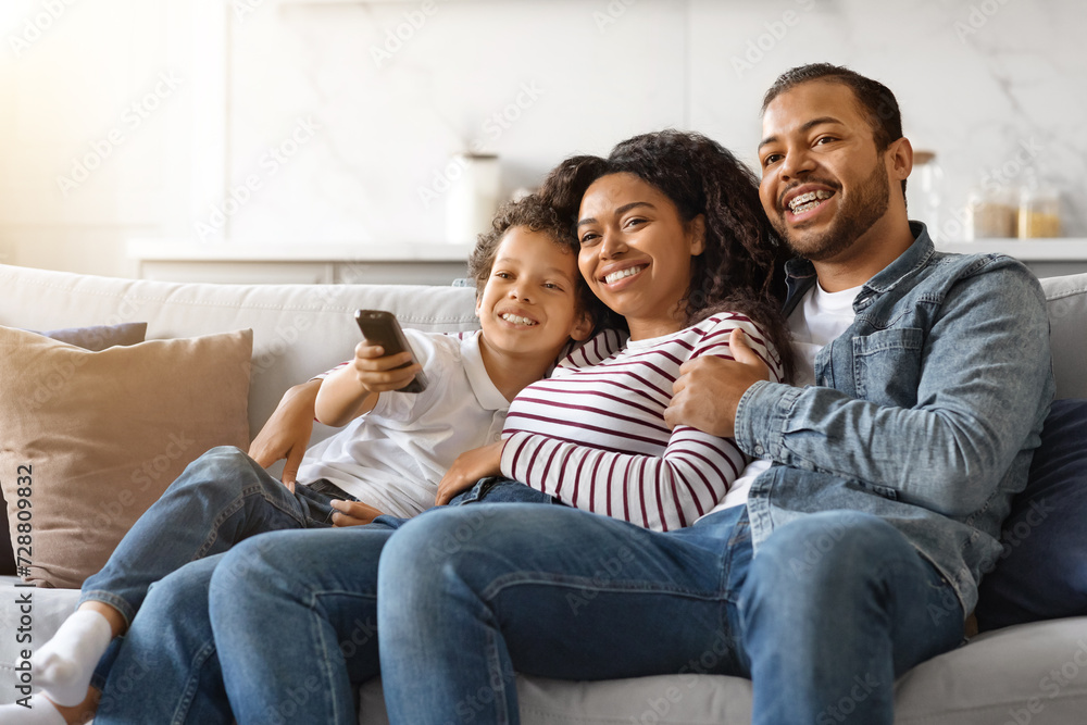 Family Weekend. Cheerful black parents and their son watching tv at home Family Weekend. Cheerful black parents and their son watching tv at home