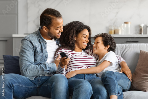 Relaxed black family lounging on the couch with remote in hand