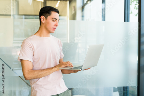 Young businessman in casual clothing using a laptop computer while standing in a meeting room