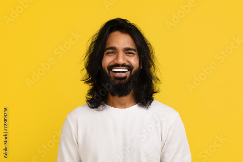 Emotional handsome millennial eastern guy laughing on yellow background © Prostock-studio
