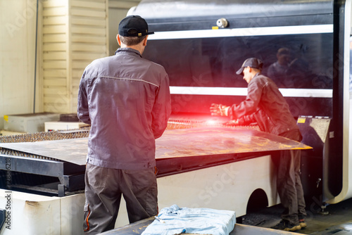 Workers are polishing metal parts in the workshop the men are using abrasive grinder to remove rust from the surface of the parts