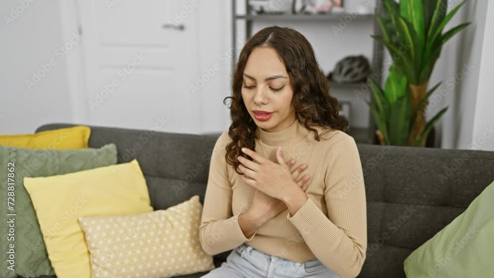 A young woman coughing while sitting on a sofa indoors, portraying health and wellness concepts in a home setting. A young woman coughing while sitting on a sofa indoors, portraying health and wellness concepts in a home setting.