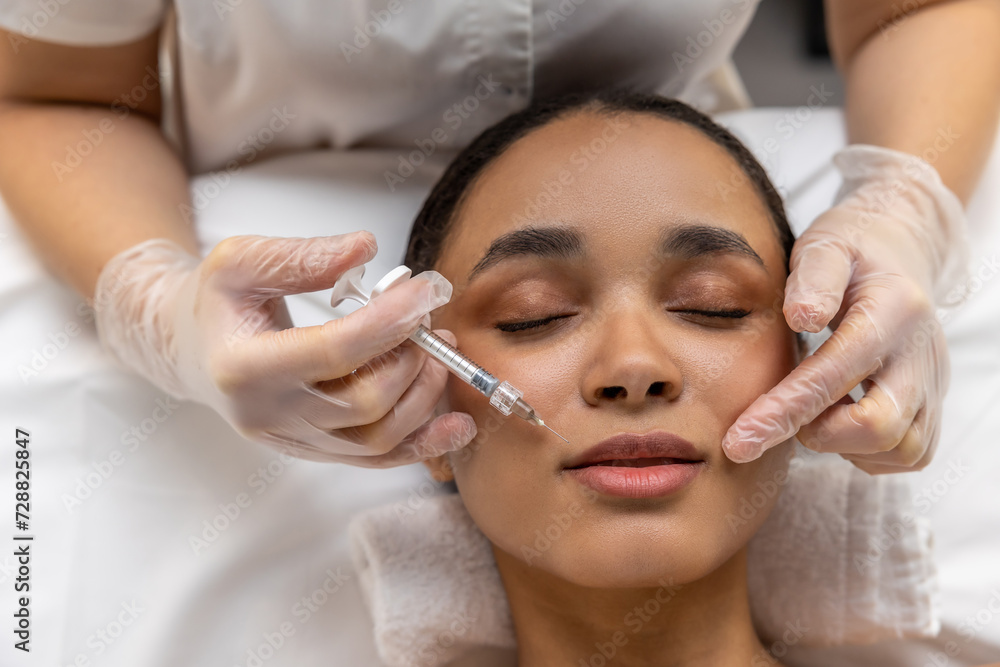 Beautician making face injections to a female patient Beautician making face injections to a female patient