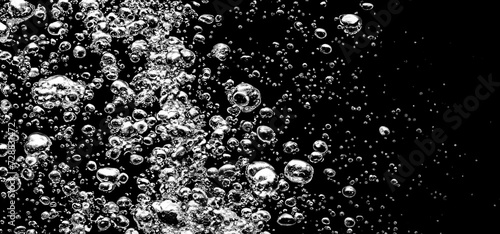 Soda water bubbles splashing underwater against black background. Soda liquid texture that fizzing and floating up to surface like a explosion in under water for refreshing carbonate drink concept. photo