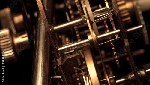clockwork mechanism of an old ALARM CLOCK  disassembled with golden cogwheels running on silver steel closeup gear movement working close-up side view detail swiss made antique watch isolated on black