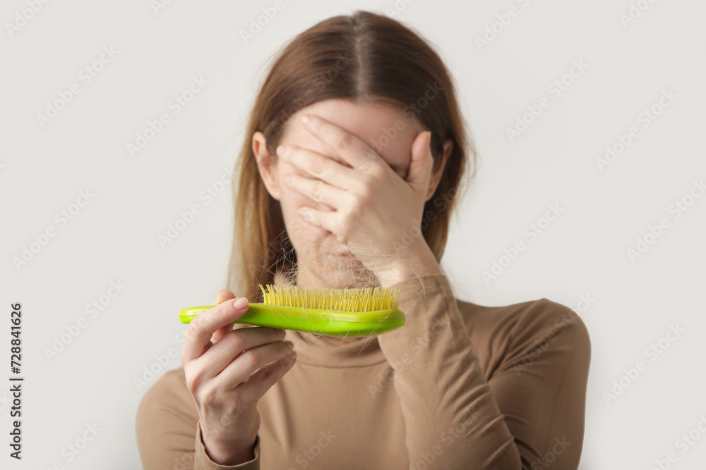 Woman holding detangler hair brush full of hair that has fallen out, loss hair problem Woman holding detangler hair brush full of hair that has fallen out, loss hair problem