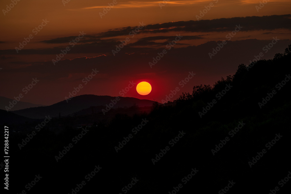 Beautiful sunset in the mountains. Sunset View from the Top of a Mountain. Sunset in strong orange tones in Serbia. The sun falls for horizon, a sunset. Shadows are condensed, beautiful clouds.