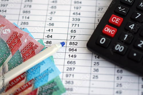 Business calculations with indonesian rupiah money bills and calculator with pen on office table close up. The concept of business and taxpaying in Indonesia photo