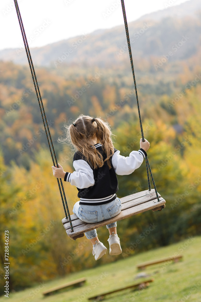Child on Swing Overlooking Autumn Forest