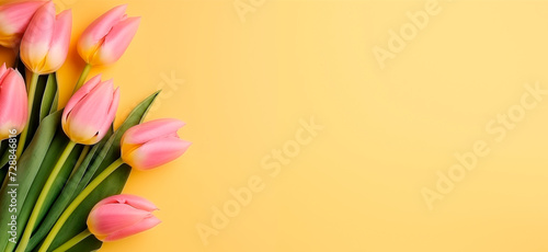 A bouquet of pink tulips lies on a yellow background, top view with copy space. Natural background. Banner with tulips