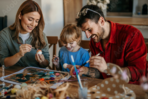 Family of three bonds over Easter egg decorating in their cozy dining room