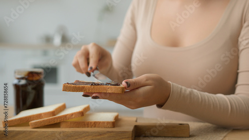 Cropped shot female hands spread chocolate paste jam on toast bread with knife cook morning breakfast order food delivery from supermarket unknown wife housewife cooking sweet sandwich in home kitchen