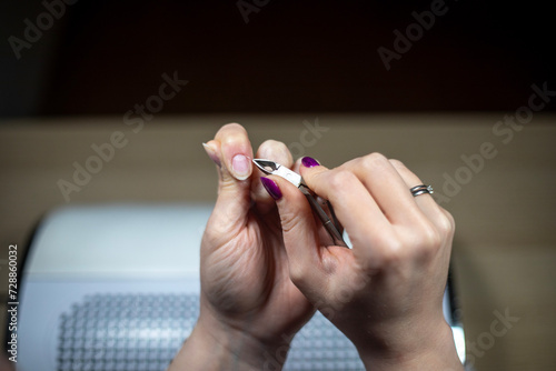 Nail technician doing her own nail, trimming her cuticle.