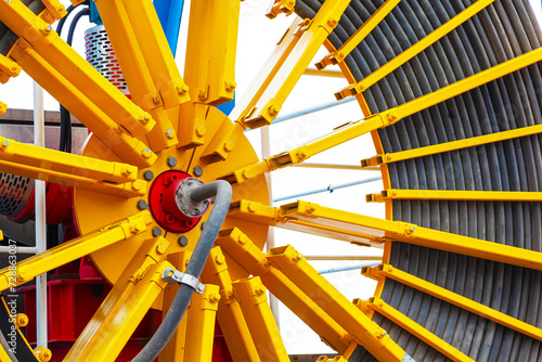 A large wheel with a harbor crane electric cable coiled around it in the port area.