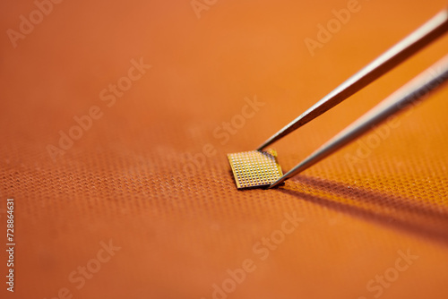 close up view of tweezers and electronic chipset on table in workshop, electronics repair business