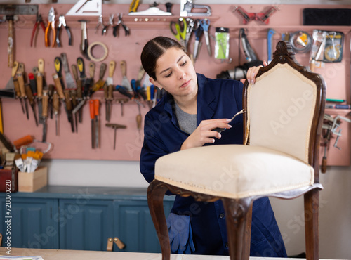Young female furniture workshop worker designing vintage chair