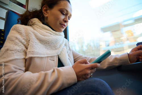 Young woman using mobile phone while travels by high speed train. Online communication. Internet. Rail road transport photo