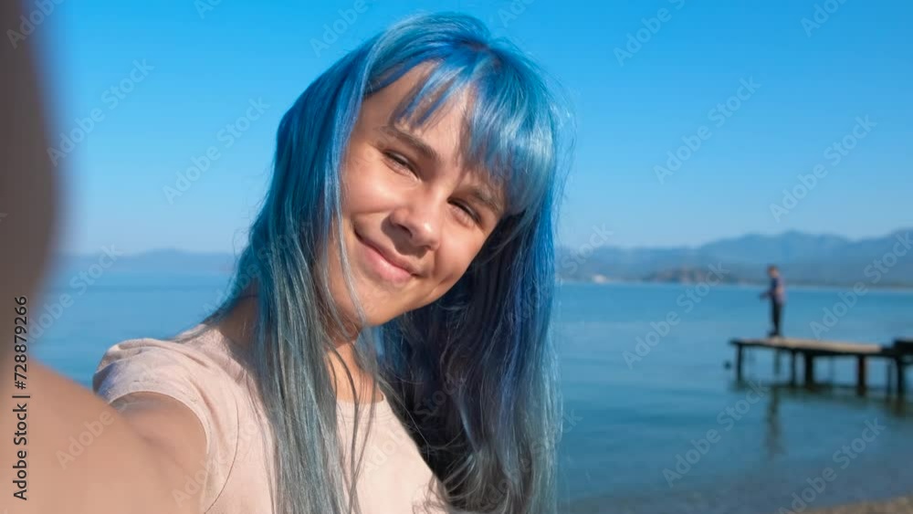 Resting blue girl with phone by turquoise sea. A view of resting blue teen with phone pass her vacation time on the beach against sunny sky. Resting blue girl with phone by turquoise sea. A view of resting blue teen with phone pass her vacation time on the beach against sunny sky.