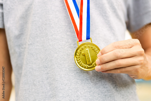 Athlete holding and proudly displaying their gold medal. Champion athlete in sporting events photo