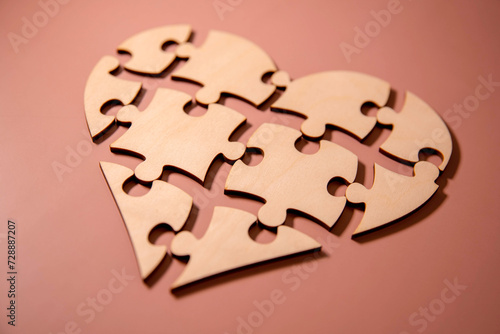 closeup of some separated pieces of a puzzle which together form a heart on a white rustic wooden surface photo