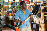 Focused adult african american man choosing shovel to working in his garden at gardening tools store..