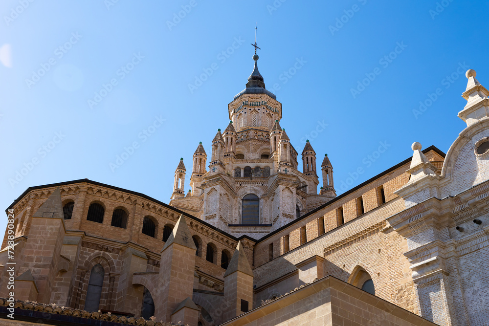 Impressive architecture of ancient Roman Catholic Cathedral Santa Maria de Huerta in Tarazona with dome tower decorated with turrets in Aragonese Mudejar style against blue sky on sunny day, Spain