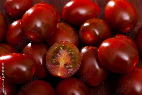 Ripe red cultivated species kumato tomatoes on wooden background. Healthy vitamin product photo
