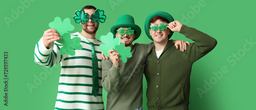 Happy young men with clovers on green background. St. Patrick s Day celebration