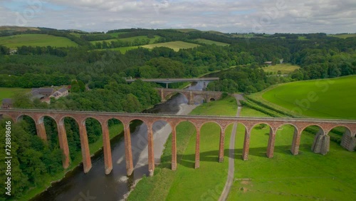 AERIAL: Flight towards spectacular Drygrange Viaduct crossing the River Tweed. Amazing Victorian railway bridge embedded in picturesque green landscape. Magnificent historic landmark worth a visit. photo