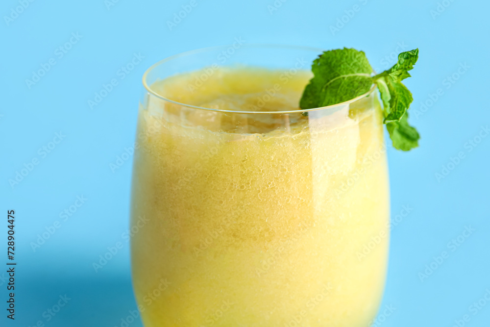 Glass of tasty melon smoothie with mint on blue background Glass of tasty melon smoothie with mint on blue background